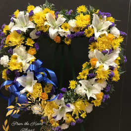 Heart-shaped floral wreath with white lilies, yellow blooms, and purple accents