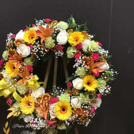 Heart-shaped floral wreath with yellow gerberas, white roses, and orange lilies