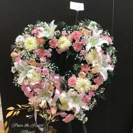 Heart-shaped floral wreath with pink and white flowers on an easel