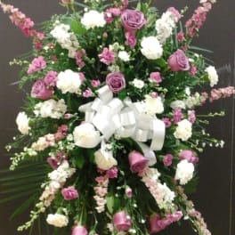 Large standing floral spray with pink and white flowers and a white ribbon bow