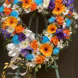 Heart-shaped floral wreath with orange roses, gerbera daisies, and blue carnations