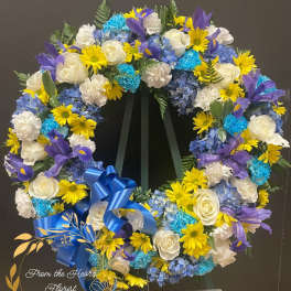 Circular floral wreath with white roses, blue hydrangeas, yellow daisies, and purple irises
