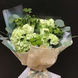 Green and white bouquet wrapped in beige paper with a ribbon