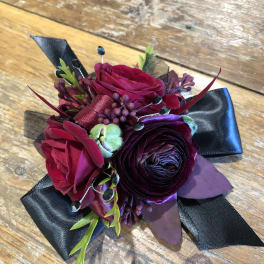 Small corsage with deep pink and purple flowers and black ribbon