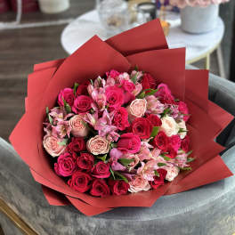 Bouquet of pink and red roses with pale pink alstroemeria in red wrap