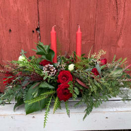 Red roses and greenery arranged with two red candles