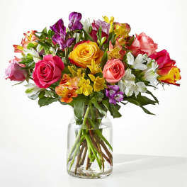 Mixed bouquet of colorful roses and alstroemeria in a clear glass vase