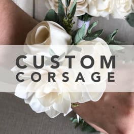 White floral corsage with roses and greenery on a wrist