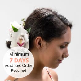 White orchid hair flower worn behind the ear on a woman with dark hair in profile