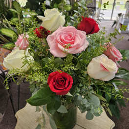 Arrangement of pink, red, and white roses in a clear glass vase