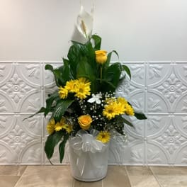 Yellow flowers and white blooms in a white bucket vase