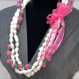 Braided white and pink floral lei with a bright pink ribbon bow displayed on a dark mannequin.