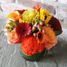 Colorful mixed bouquet in a low green vase with gerbera daisies and roses