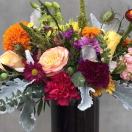 Colorful mixed bouquet in a dark vase with roses and carnations