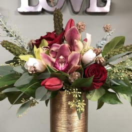 Mixed bouquet with roses, orchids, and tulips in a gold vase