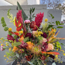 Tropical mixed bouquet in a glass vase with bright pink, orange, and yellow blooms