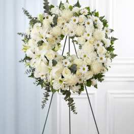 Standing white floral wreath with roses, lilies and mums on a metal easel
