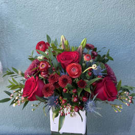 Red rose and mixed bloom arrangement in a white vase