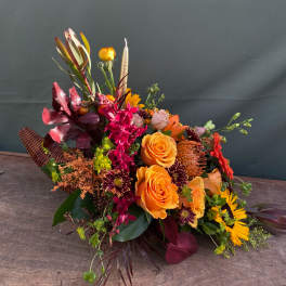 Colorful bouquet with orange roses and burgundy accents in a woven basket