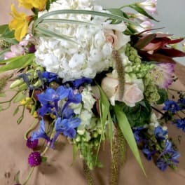 Large mixed bouquet with white hydrangea, yellow lilies, and blue flowers