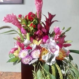 Tall tropical bouquet with pink and white flowers in a dark vase