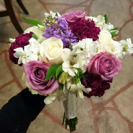 Handheld bouquet of pink, white, purple, and burgundy flowers