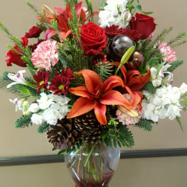 Red and white floral arrangement in a glass vase with lilies and roses