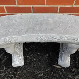 Decorative stone garden bench against a brick wall