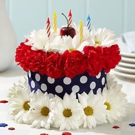 Cake decorated with red and white flowers and striped candles