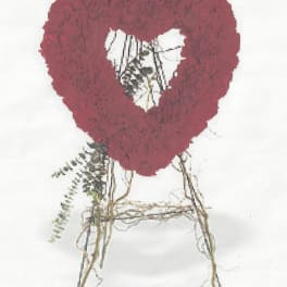 Heart-shaped red floral wreath with a white center on a stand