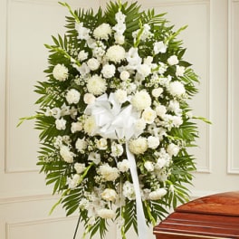 White funeral spray with a ribbon on a stand