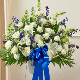 White floral spray with blue accents and a large blue ribbon