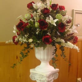 Red roses and white lilies arranged in a white pedestal vase