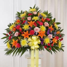 Large colorful floral standing spray with a yellow ribbon
