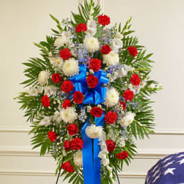 Standing floral spray with red and white flowers and a blue ribbon