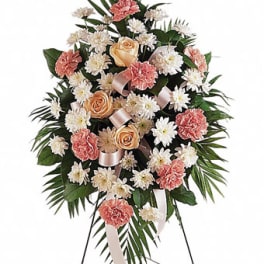 Standing floral spray with pink carnations, peach roses, and white daisies