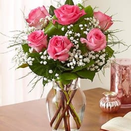 Pink roses arranged in a clear glass vase with baby's breath.