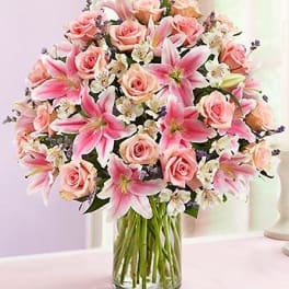 Pink roses and lilies arranged in a clear glass vase