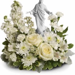White floral arrangement with a small religious statue in the center