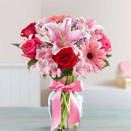Pink and red mixed bouquet in a glass vase with a pink ribbon
