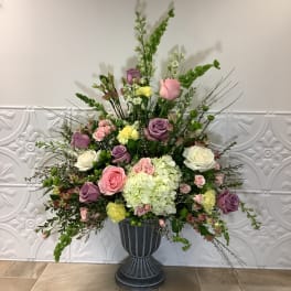 Large mixed flower arrangement in a dark pedestal vase