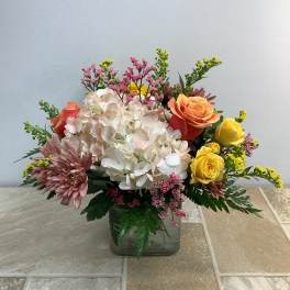 Mixed bouquet with hydrangea, roses, and mums in a glass vase