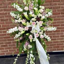Large standing floral spray with pink and white flowers on a black easel