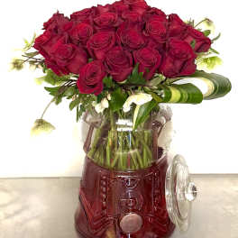 Red rose bouquet in a clear glass vase with a red base