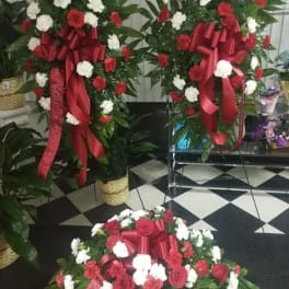 Three red and white floral standing sprays with ribbon bows