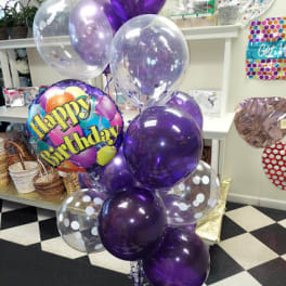 Cluster of purple and clear birthday balloons with a Happy Birthday balloon