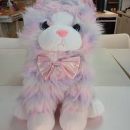 Pastel plush cat with a pink bow sitting on a table