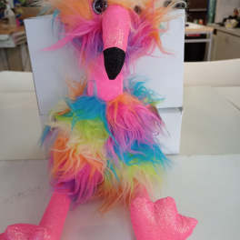 Rainbow plush bird toy with fuzzy multicolor fur and glittery pink beak and feet