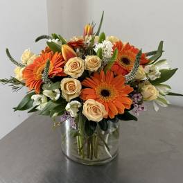 Orange gerbera daisies and cream roses in a glass vase