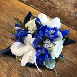Blue and white floral corsage with ribbon and pearl accents